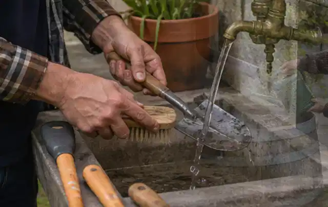 Hände reinigen gebrauchte Gartengeräte mit Bürste und Wasser am Außenbecken; Thema Mähroboter Messer, Schwerpunkt Systemvergleich; Kontrolle.