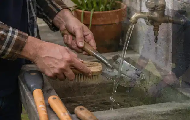 Hände reinigen gebrauchte Gartengeräte mit Bürste und Wasser am Außenbecken; Thema Mammotion Luba, Schwerpunkt Sicherheit; Kontrolle.