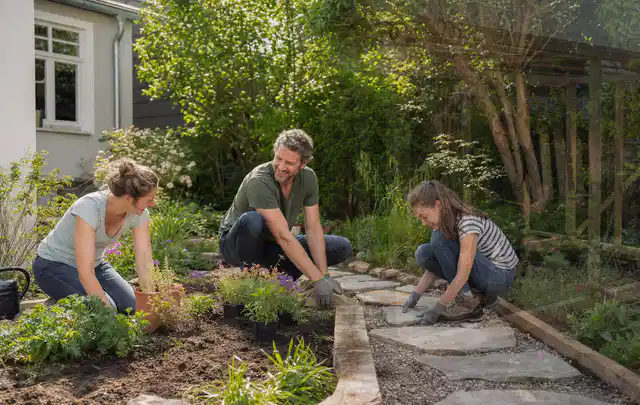 Familie geht auf einem Weg durch einen abwechslungsreich gestalteten Garten; Thema Mediterraner Garten, Schwerpunkt Beleuchtung; Praxisalltag.