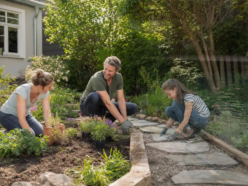 Familie geht auf einem Weg durch einen abwechslungsreich gestalteten Garten; Thema Mediterraner Garten, Schwerpunkt Praxisbeispiele; Titelbild.