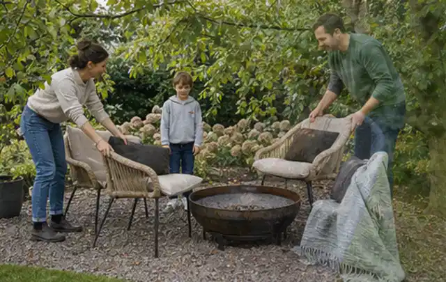 Familie stellt wetterfeste Sessel an einem geschützten Sitzplatz im Garten auf; Thema Metallzäune, Schwerpunkt Checkliste; Umsetzung.