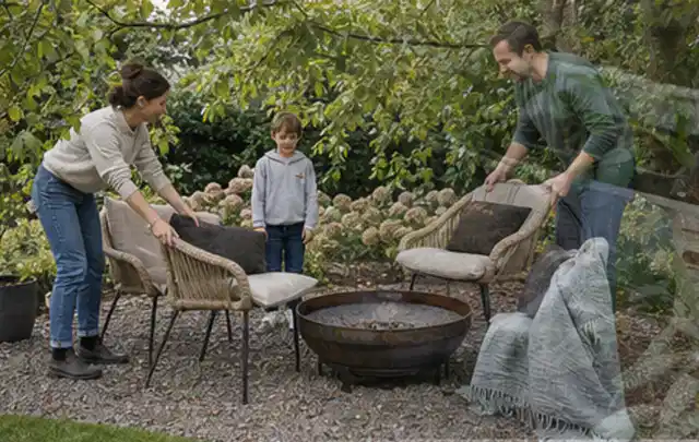 Familie stellt wetterfeste Sessel an einem geschützten Sitzplatz im Garten auf; Thema Metallzäune, Schwerpunkt Fundament; Umsetzung.