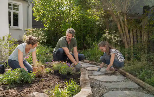 Familie geht auf einem Weg durch einen abwechslungsreich gestalteten Garten; Thema Metallzäune, Schwerpunkt Pflege; Praxisalltag.