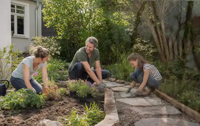 Familie geht auf einem Weg durch einen abwechslungsreich gestalteten Garten; Thema Mobiler Sichtschutz, Schwerpunkt Aufbau; Umsetzung.