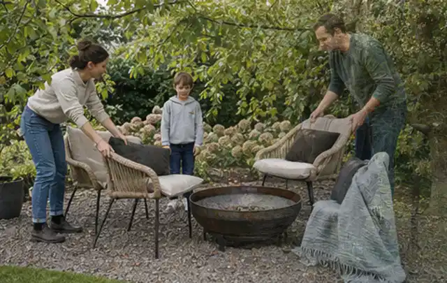 Familie stellt wetterfeste Sessel an einem geschützten Sitzplatz im Garten auf; Thema Mobiler Sichtschutz, Schwerpunkt Pflege; Kontrolle.