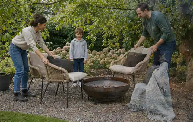 Familie stellt wetterfeste Sessel an einem geschützten Sitzplatz im Garten auf; Thema Mobiler Sichtschutz, Schwerpunkt Planung; Umsetzung.