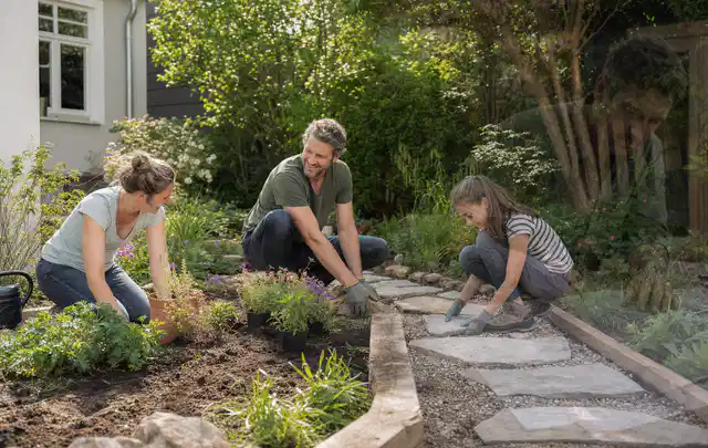 Familie geht auf einem Weg durch einen abwechslungsreich gestalteten Garten; Thema Mobiler Sichtschutz, Schwerpunkt Planung; Praxisalltag.