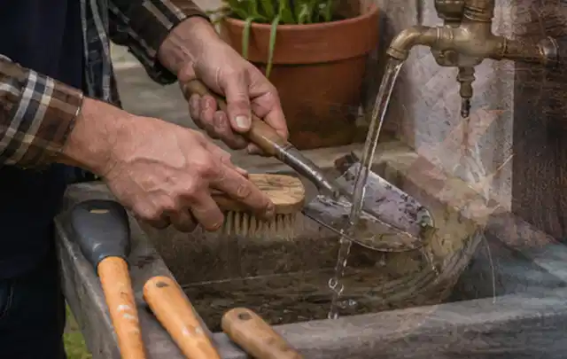 Hände reinigen gebrauchte Gartengeräte mit Bürste und Wasser am Außenbecken; Thema Modelle, Schwerpunkt Mähroboter; Umsetzung.