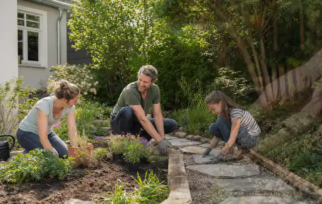 Familie geht auf einem Weg durch einen abwechslungsreich gestalteten Garten; Thema Moderner Garten, Schwerpunkt Beleuchtung; Kontrolle.