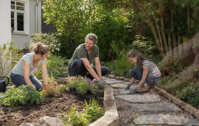 Familie geht auf einem Weg durch einen abwechslungsreich gestalteten Garten; Thema Moderner Garten, Schwerpunkt Bepflanzung; Kontrolle.