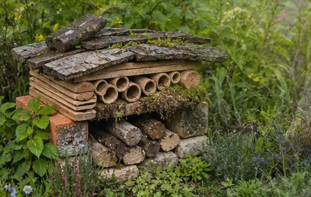 Naturnaher Unterschlupf aus Holz Rinde und Pflanzenstängeln im Garten; Thema Moderner Garten, Schwerpunkt Hanglage; Umsetzung.