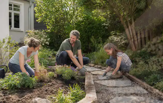 Familie geht auf einem Weg durch einen abwechslungsreich gestalteten Garten; Thema Moderner Garten, Schwerpunkt Kosten; Kontrolle.