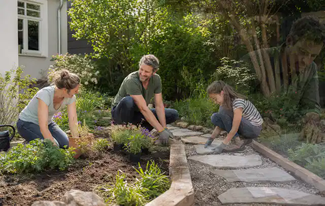 Familie geht auf einem Weg durch einen abwechslungsreich gestalteten Garten; Thema Moderner Garten, Schwerpunkt Materialwahl; Ergebnis.