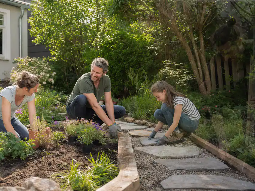 Familie geht auf einem Weg durch einen abwechslungsreich gestalteten Garten; Thema Naturgarten, Schwerpunkt Praxisbeispiele; Titelbild.