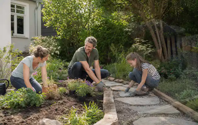 Familie geht auf einem Weg durch einen abwechslungsreich gestalteten Garten; Thema Naturgarten, Schwerpunkt Privatsphäre; Umsetzung.