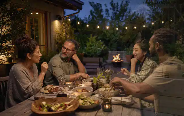 Menschen verbringen einen ruhigen Abend an einem Sitzplatz im Garten; Thema Outdoor Küchen, Schwerpunkt Anwendung; Praxisalltag.