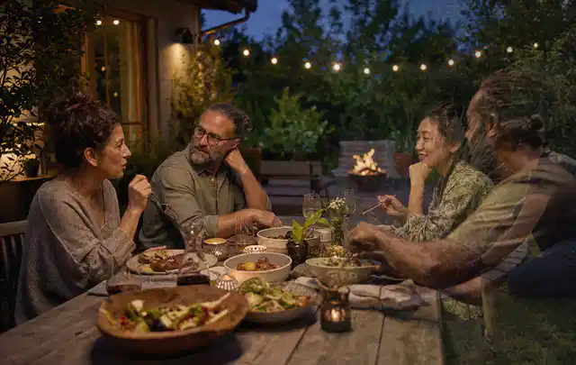 Menschen verbringen einen ruhigen Abend an einem Sitzplatz im Garten; Thema Outdoor Küchen, Schwerpunkt Fehlerhilfe; Umsetzung.