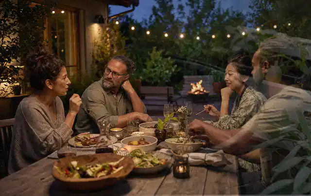 Menschen verbringen einen ruhigen Abend an einem Sitzplatz im Garten; Thema Outdoor Küchen, Schwerpunkt Gärten mit kleiner Fläche; Kontrolle.