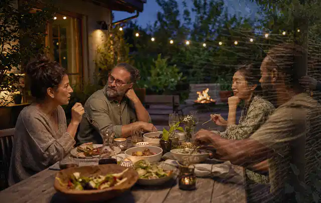Menschen verbringen einen ruhigen Abend an einem Sitzplatz im Garten; Thema Outdoor Küchen, Schwerpunkt Kaufberatung; Umsetzung.