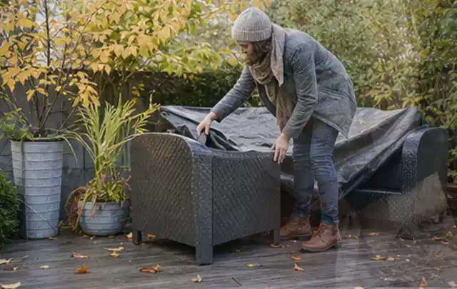 Person deckt Gartenmöbel vor der kalten Jahreszeit sorgfältig ab; Thema Outdoor Küchen, Schwerpunkt Kaufberatung; Ergebnis.