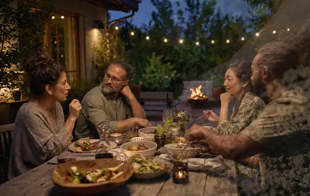 Menschen verbringen einen ruhigen Abend an einem Sitzplatz im Garten; Thema Outdoor Küchen, Schwerpunkt Nachhaltigkeit; Ausgangslage.