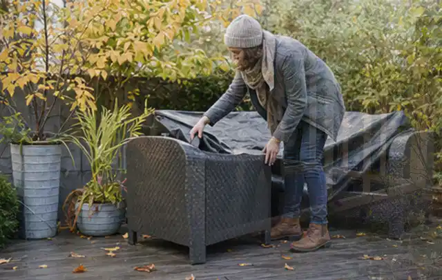 Person deckt Gartenmöbel vor der kalten Jahreszeit sorgfältig ab; Thema Outdoor Küchen, Schwerpunkt Nachhaltigkeit; Ergebnis.