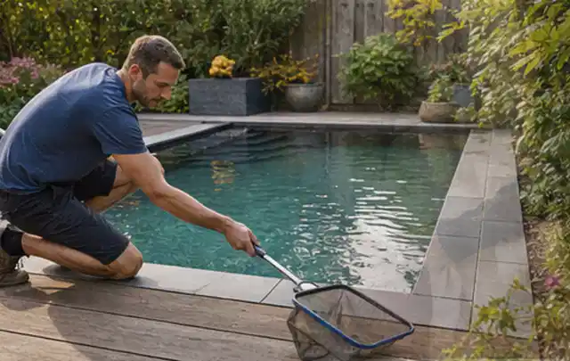 Person entfernt Blätter mit einem Kescher aus einem kleinen Gartenpool; Thema Outdoor Küchen, Schwerpunkt Outdoor Freizeit; Kontrolle.