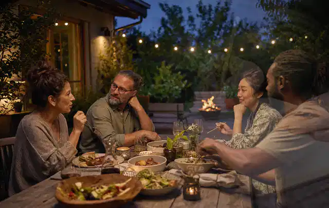 Menschen verbringen einen ruhigen Abend an einem Sitzplatz im Garten; Thema Outdoor Küchen, Schwerpunkt Reinigung; Praxisalltag.