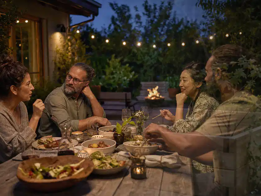 Menschen verbringen einen ruhigen Abend an einem Sitzplatz im Garten; Thema Outdoor Küchen, Schwerpunkt Sicherheit; Titelbild.