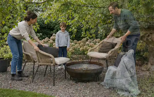 Familie stellt wetterfeste Sessel an einem geschützten Sitzplatz im Garten auf; Thema Outdoor Küchen, Schwerpunkt Sicherheit; Kontrolle.
