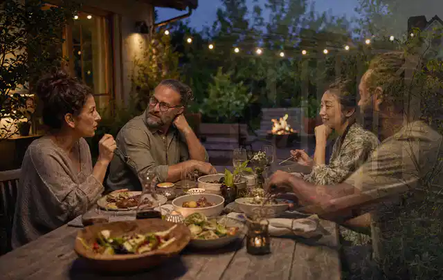 Menschen verbringen einen ruhigen Abend an einem Sitzplatz im Garten; Thema Outdoor Küchen, Schwerpunkt Systemvergleich; Umsetzung.