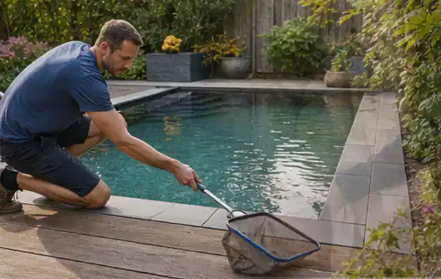Person entfernt Blätter mit einem Kescher aus einem kleinen Gartenpool; Thema Outdoor Küchen, Schwerpunkt Vergleich; Praxisalltag.