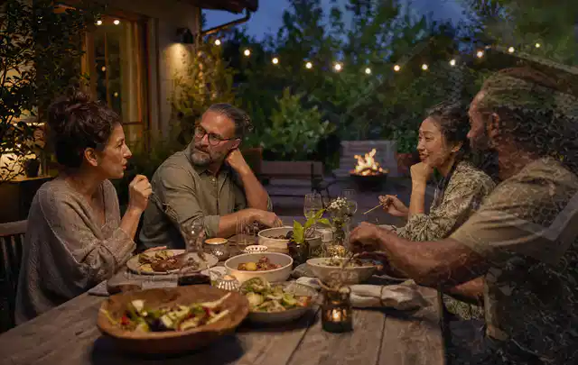Menschen verbringen einen ruhigen Abend an einem Sitzplatz im Garten; Thema Outdoor Küchen, Schwerpunkt Winterlager; Umsetzung.