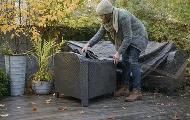 Person deckt Gartenmöbel vor der kalten Jahreszeit sorgfältig ab; Thema Pelletgrills, Schwerpunkt Checkliste; Ergebnis.