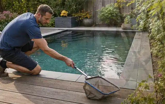 Person entfernt Blätter mit einem Kescher aus einem kleinen Gartenpool; Thema Pelletgrills, Schwerpunkt Fehlerhilfe; Kontrolle.