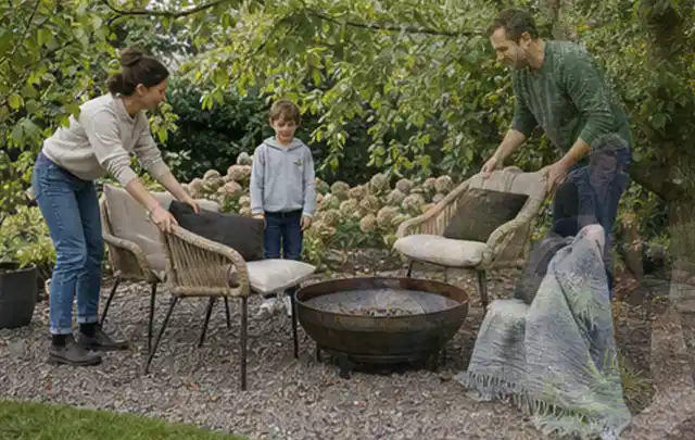 Familie stellt wetterfeste Sessel an einem geschützten Sitzplatz im Garten auf; Thema Pelletgrills, Schwerpunkt Gärten mit kleiner Fläche; Umsetzung.