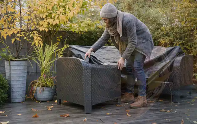 Person deckt Gartenmöbel vor der kalten Jahreszeit sorgfältig ab; Thema Pelletgrills, Schwerpunkt Kosten; Ergebnis.
