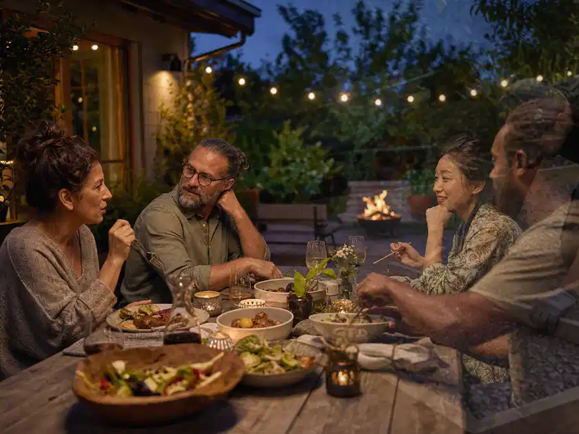 Menschen verbringen einen ruhigen Abend an einem Sitzplatz im Garten; Thema Pelletgrills, Schwerpunkt Winterlager; Titelbild.