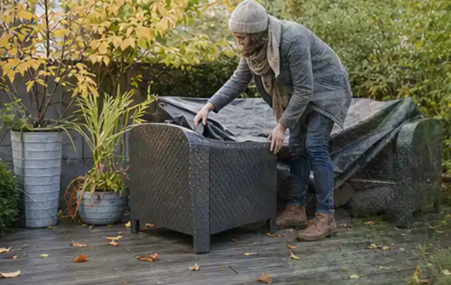 Person deckt Gartenmöbel vor der kalten Jahreszeit sorgfältig ab; Thema Pergolen, Schwerpunkt Outdoor Freizeit; Ausgangslage.