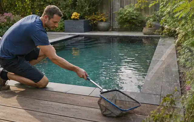 Person entfernt Blätter mit einem Kescher aus einem kleinen Gartenpool; Thema Pergolen, Schwerpunkt Wartung; Ausgangslage.