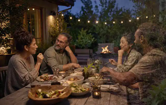 Menschen verbringen einen ruhigen Abend an einem Sitzplatz im Garten; Thema Pergolen, Schwerpunkt Winterlager; Umsetzung.