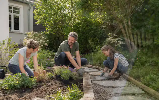 Familie geht auf einem Weg durch einen abwechslungsreich gestalteten Garten; Thema Pflegeleichter Garten, Schwerpunkt Kosten; Umsetzung.