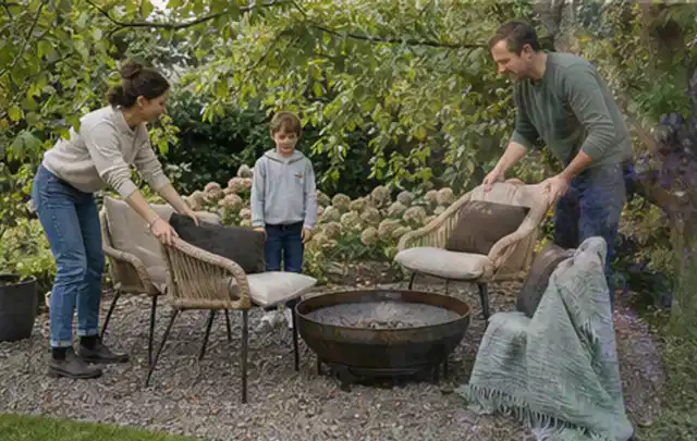 Familie stellt wetterfeste Sessel an einem geschützten Sitzplatz im Garten auf; Thema Pflegeleichter Garten, Schwerpunkt Materialwahl; Kontrolle.