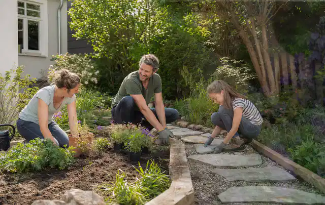 Familie geht auf einem Weg durch einen abwechslungsreich gestalteten Garten; Thema Pflegeleichter Garten, Schwerpunkt Privatsphäre; Kontrolle.