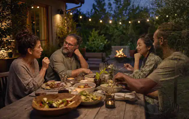 Menschen verbringen einen ruhigen Abend an einem Sitzplatz im Garten; Thema Pizzaöfen, Schwerpunkt Ersatzteile; Umsetzung.
