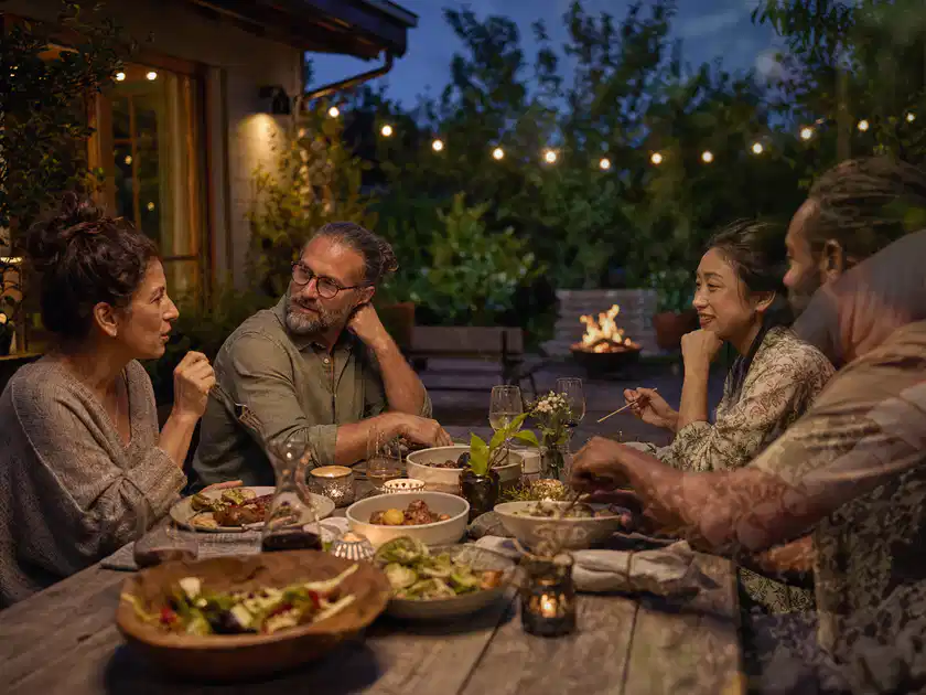 Menschen verbringen einen ruhigen Abend an einem Sitzplatz im Garten; Thema Pizzaöfen, Schwerpunkt Fehlerhilfe; Titelbild.