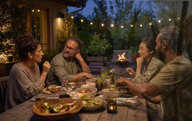 Menschen verbringen einen ruhigen Abend an einem Sitzplatz im Garten; Thema Pizzaöfen, Schwerpunkt Testkriterien; Kontrolle.