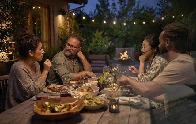 Menschen verbringen einen ruhigen Abend an einem Sitzplatz im Garten; Thema Poolabdeckungen, Schwerpunkt Fehlerhilfe; Praxisalltag.