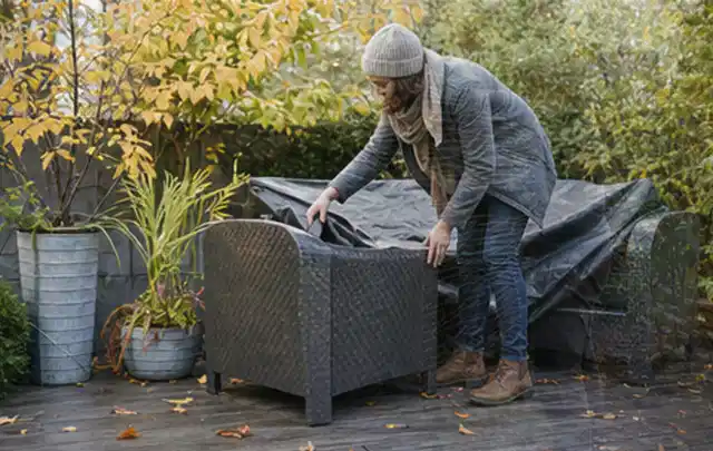 Person deckt Gartenmöbel vor der kalten Jahreszeit sorgfältig ab; Thema Poolabdeckungen, Schwerpunkt Kaufberatung; Kontrolle.