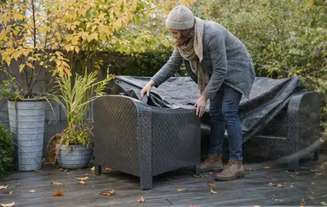 Person deckt Gartenmöbel vor der kalten Jahreszeit sorgfältig ab; Thema Poolchemie, Schwerpunkt Nachhaltigkeit; Kontrolle.
